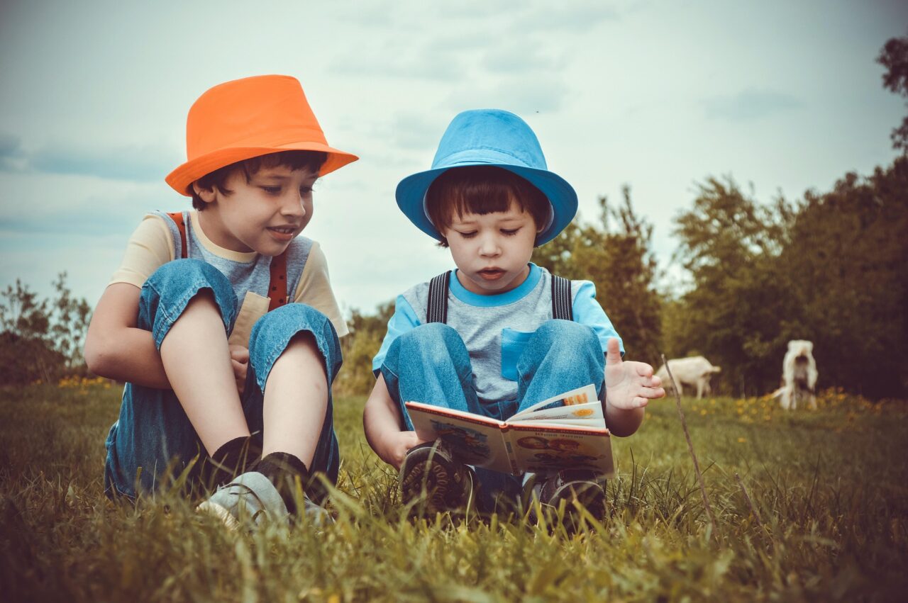 Niños leyendo sentados en el campo.